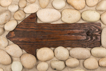 Classical wooden arrow and white stones on the sand.
