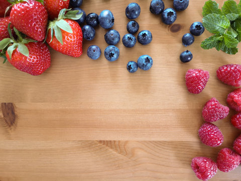Berries mix strawberries blueberries raspberries mint on the wooden table