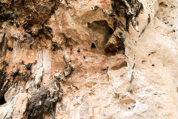 Young man climbing on a limestone cliff in Railay Beach Krabi, Thailand