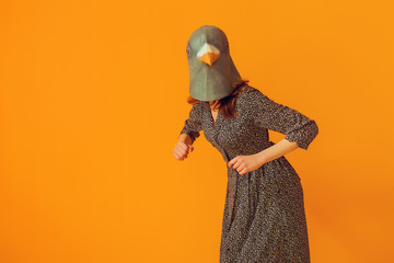 Woman funny portrait wearing pigeon mask and doing chicken imitation