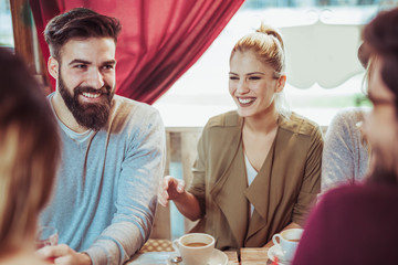 Group of five friends having a coffee together. Friends at cafe talking laughing and enjoying their time
