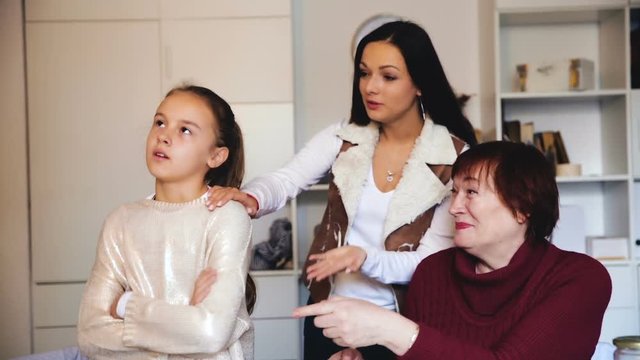 Frustrated girl sitting at home while mother and grandmother berating her