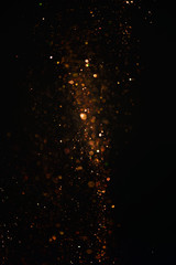 Golden glitter texture with a dark background. Defocused bokeh effect for a Christmas or wedding card.