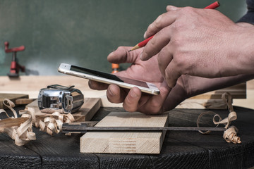 carpenter in the workshop with a red pencil looking at the blueprints