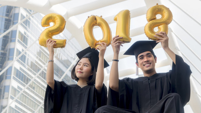 students in graduation suit sit and gold number balloons 2018
