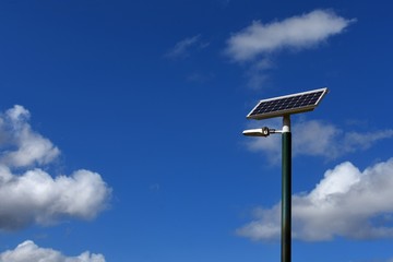 Naklejka na ściany i meble Solar electricity panel on a pole with a blue sky background