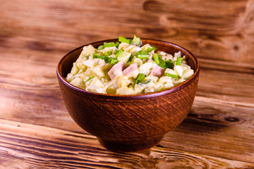 Ceramic bowl with russian traditional salad olivier on wooden table
