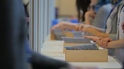 Businesswoman entry for check-in to symposium, wait holding phone in hands. Many visitors walk in building. Workshop presents representative speaker with financial project about marketing and sales