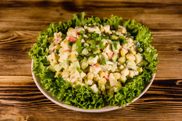 Ceramic plate with salad from crab sticks on wooden table