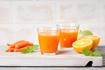 Glasses with carrot juice, apple, sliced orange and mint leaf 