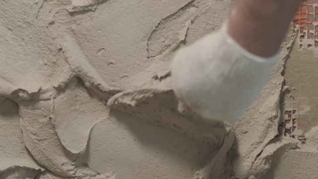 Slow motion handheld shot of worker applying plaster on the wall