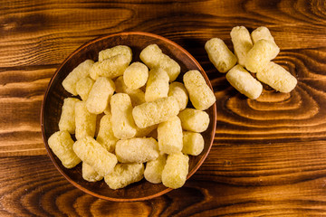Ceramic plate with corn sticks on wooden table. Top view