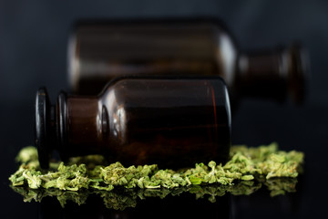 Medical Cannabis - view of marijuana and antique apothecary brown jar on the black mirror background.