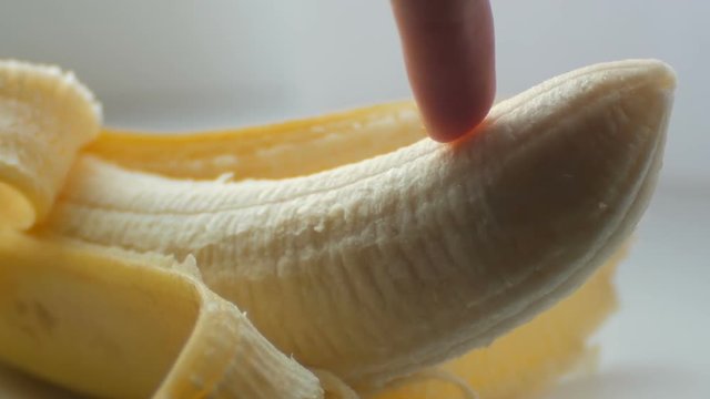 Woman sexually touching with a finger of purified banana, macro close up view