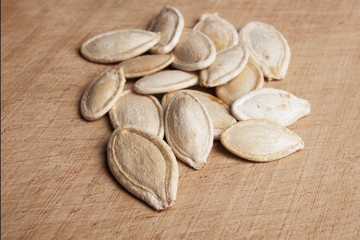 Heap of pumpkin seeds on wooden cutting board