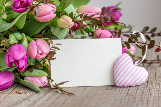 beautiful bouquet of pink and violet tulips with a heart and a white copy space on a wooden background
