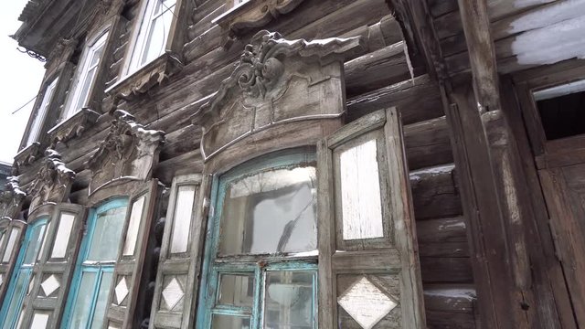 Cold Siberian winter wooden old house windows detail. Unique authentic Russian style wood carving architecture. Irkutsk center tourist attraction. White snow wind blizzard. Gimbal professional 4k