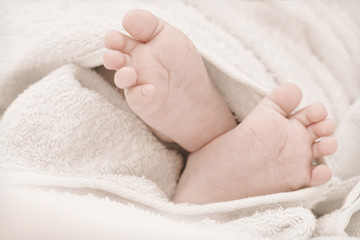 Newborn baby feet on a white towel.Toned