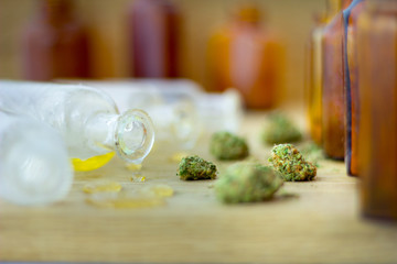 Medical Oil of Cannabis -  view of marijuana oil, leaking resin from old antique apothecary jar and marijuana flowers on fresh oak wood background.
