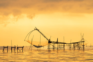 Fototapeta na wymiar Beautiful sunrise behind fishing net at Pakpra, Phatthalung, Thailand