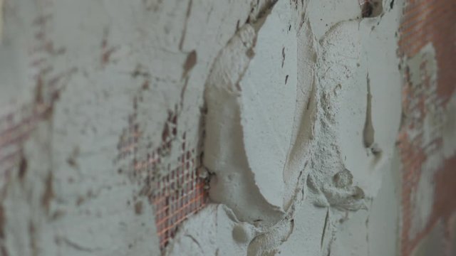 Slow motion pan shot of worker applying plaster on the wall