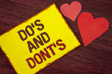 Conceptual hand writing showing Do'S And Don'Ts. Business photo text What can be done and what cannot be knowing right wrong written on Yellow Sticky note paper on wooden background Hearts.
