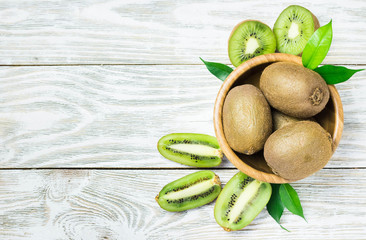 Raw fresh kiwi in a bowl on white shabby wooden background. Top view, copy space.