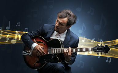 Obraz premium Young male musician playing on his guitar with musical notes around