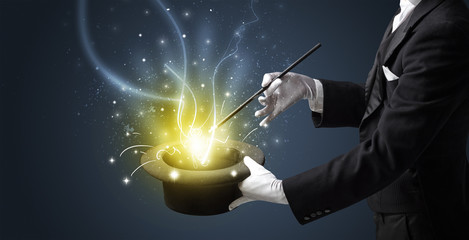 Magician hand conjure with wand  light from a black cylinder