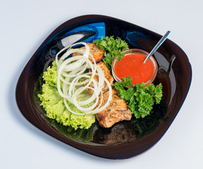 Grilled with herbs and salad leaves on a black plate on a white background