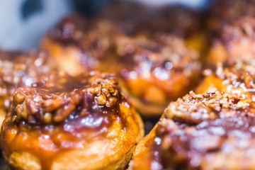 Macro closeup display of chocolate drizzled pecan nut sticky buns danish pastries caramelized in...