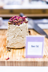 Macro closeup of large whole sweet sesame seed paste tahini halvah in Middle Eastern market with Rose Oil sign wooden