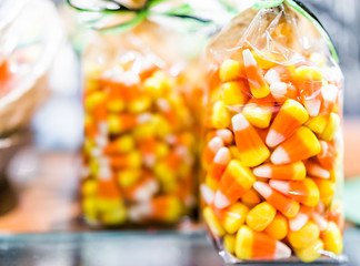 Closeup of colorful orange yellow candy corn on display packaged in plastic bag in candy store shop for Halloween holiday season trick or treat background