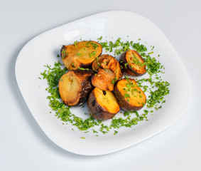 Roasted potato on black plate on white background