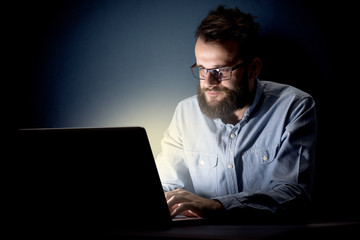 Young handsome businessman working late at night in the office with a dark background