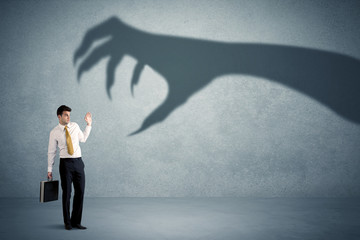 Obraz premium Business person afraid of a big monster claw shadow concept on background