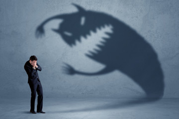 Business man afraid of his own shadow monster concept on grungy background