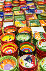 Fototapeta na wymiar Colourful hand painted bowls and pots arranged in rows on market stall