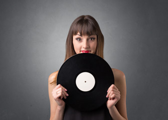 Young lady holding vinyl record on a grey background