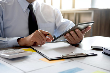 Business Financing Accounting Banking Concept, businessman using tablet and doing finances, calculate about cost to real estate investment and in other, tax system