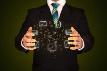 Businessman holding icons related to devices and communication 