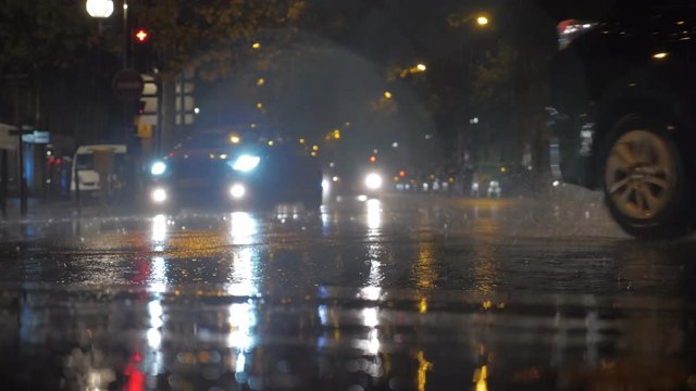 PARIS, FRANCE - SEPTEMBER 29, 2017: Slow motion shot of cars with bright head lights driving in city street at rainy night
