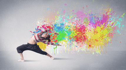 A funky contemporary hip hop dancer dancing in front of grey background with colorful bright paint splatter concept