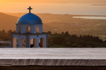 Empty old plank table with wonderful Greece landscape and characteristic belfry tower of temple.