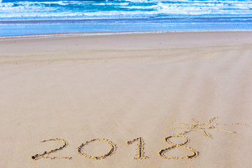 2018 inscription on wet beach sand and sea waves on background