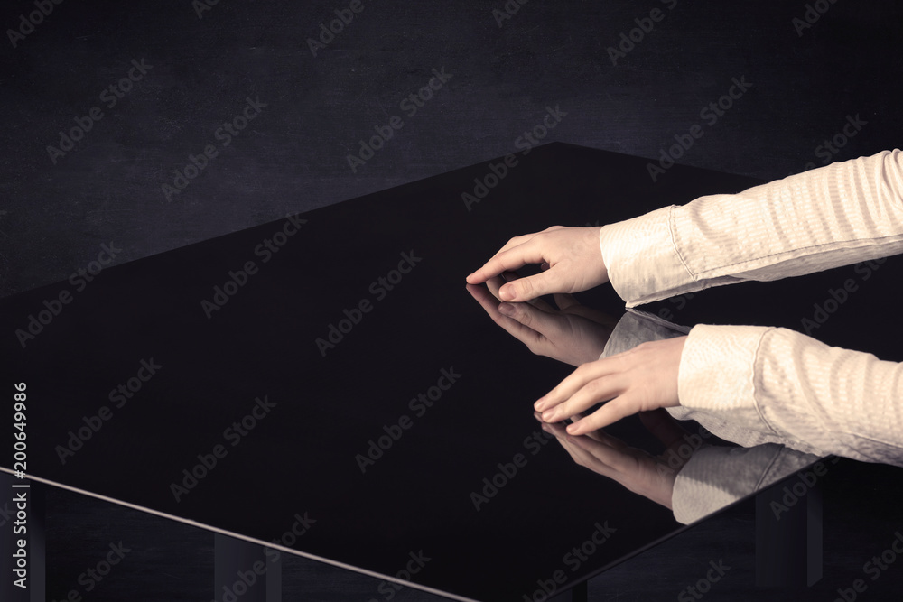 Poster Close up of a hand touching smart table with copy space on black background