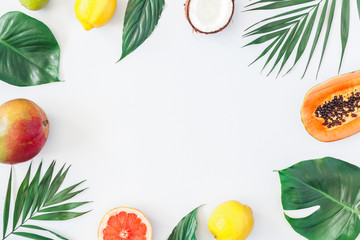 Summer tropical composition. Green palm leaves and tropical fruits on gray background. Summer concept. Flat lay, top view, copy space