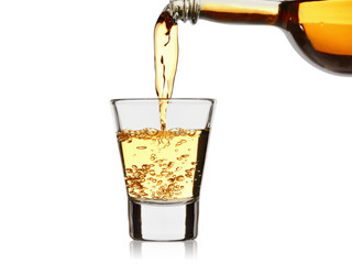 strong alcoholic drink pour from a bottle into a wineglass isolated on a white background