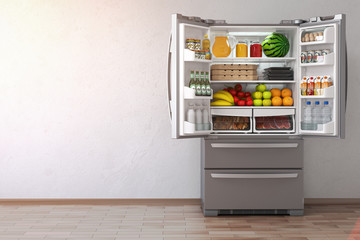 Open fridge  refrigerator full of food in the empty kitchen interior.