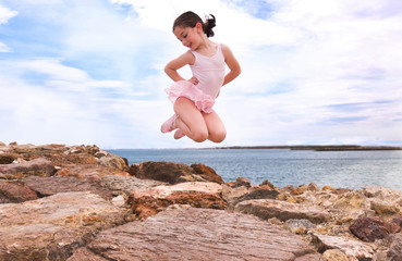 little girl jumping in a rocks beach